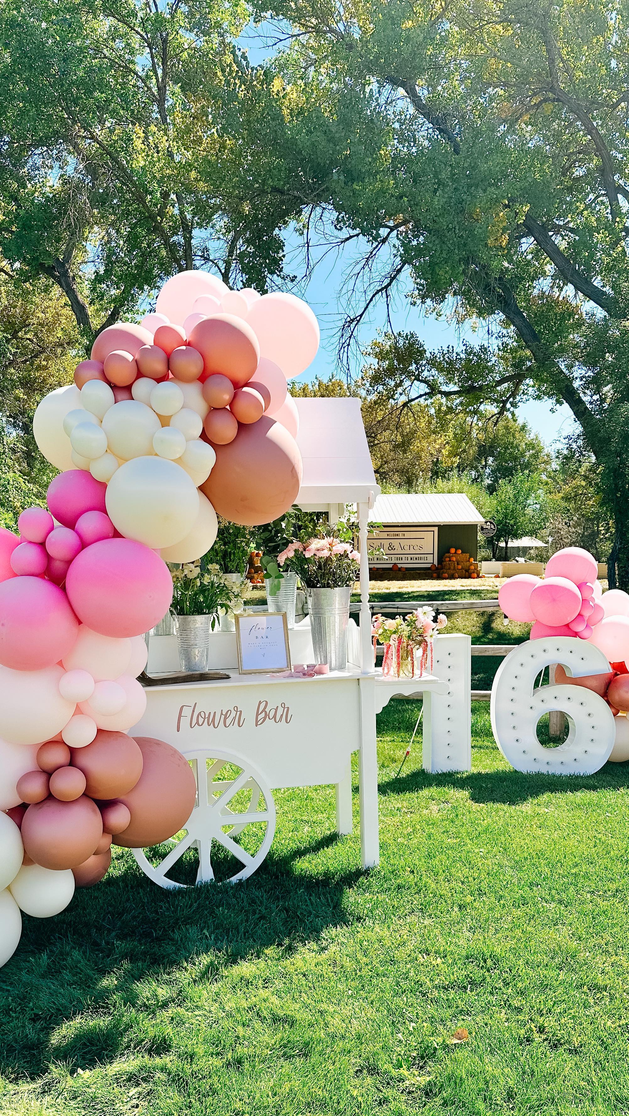 Outdoor flower bar with pink balloon arch