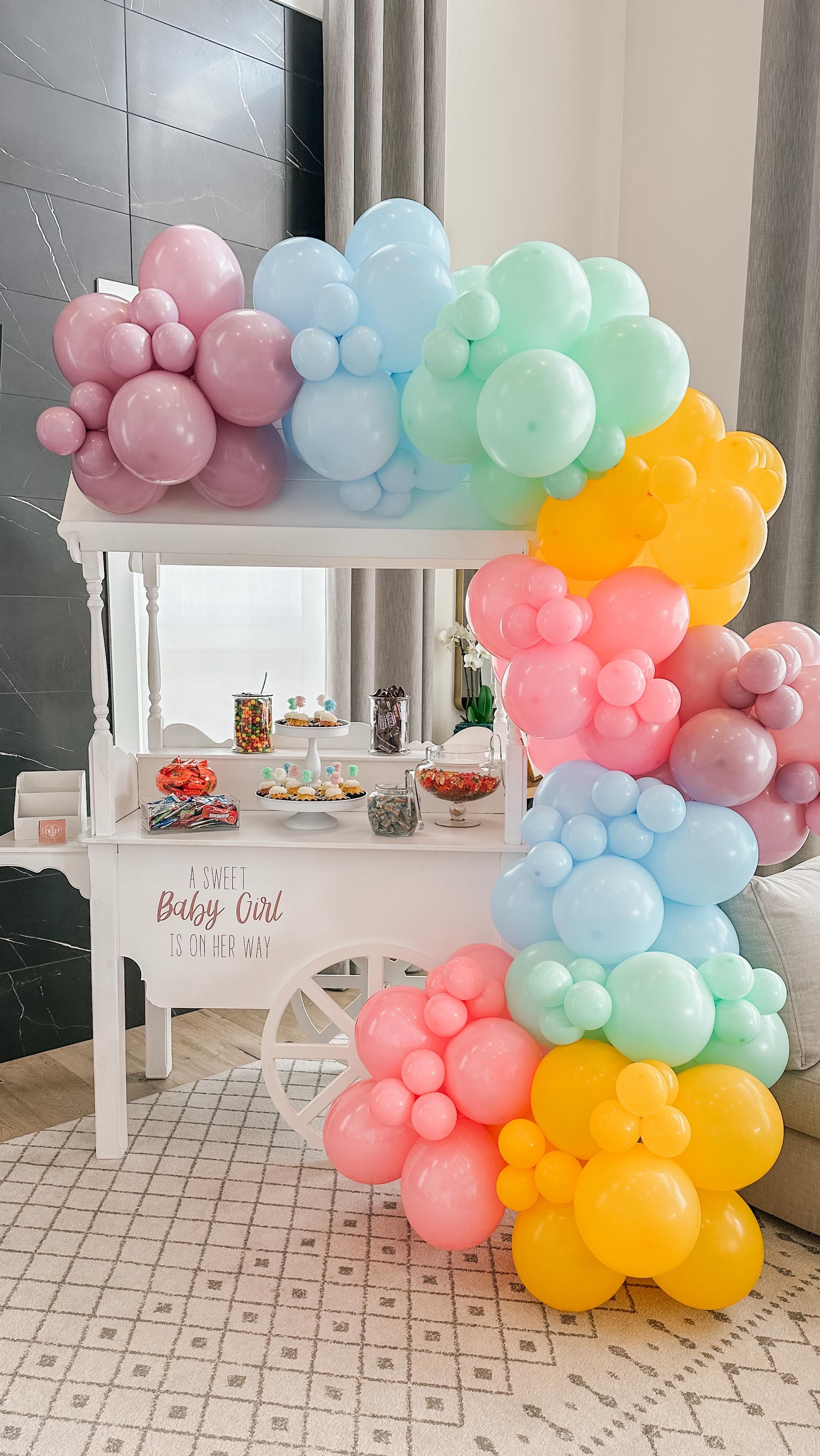 Baby shower cart with rainbow pastel balloon arch